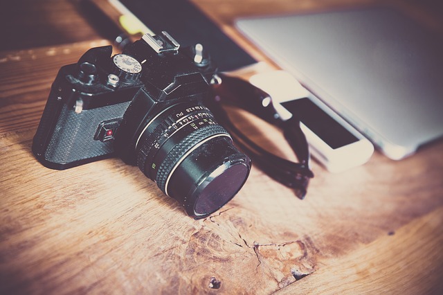 An old style SLR camera sits on a wooden desk